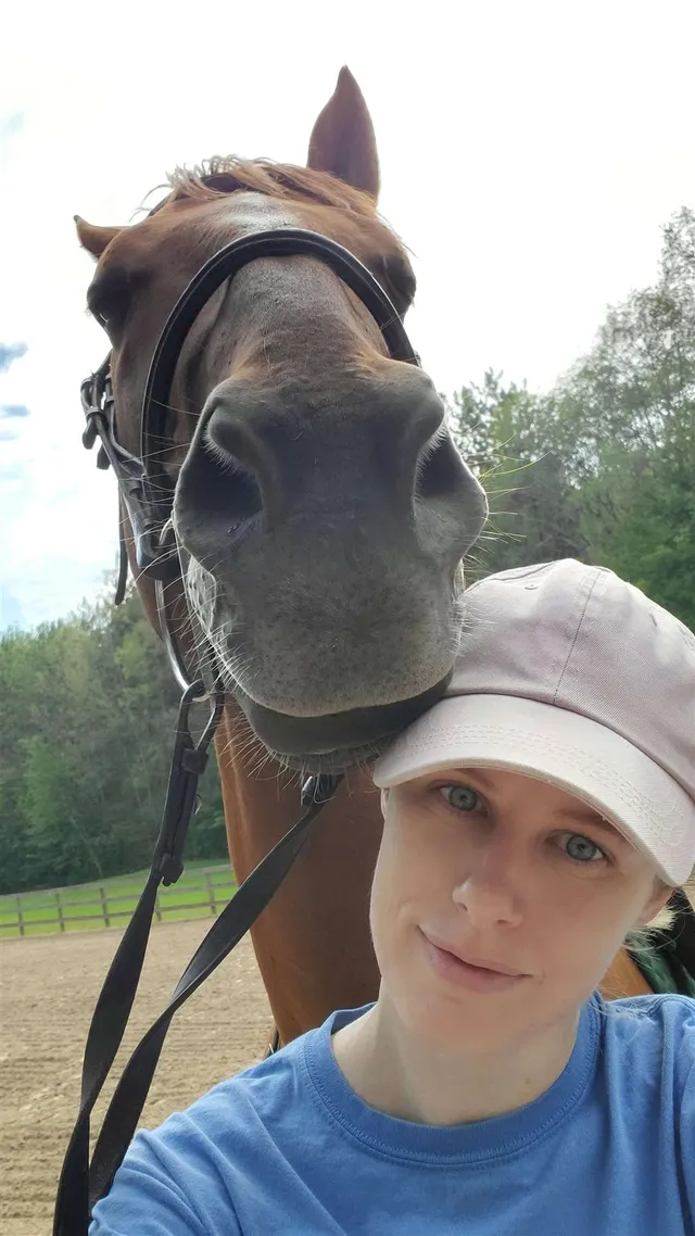 Katheryn in a pink cap, smiling, while Charlie rests his muzzle against her head